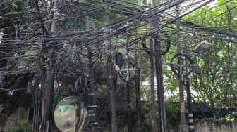 Instalasi kabel yang semrawut terlihat di Jalan Kemang Utara, Mampang Prapatan, Jakarta Selatan, Rabu (7/12/2022). [Suara.com/Alfian Winanto]