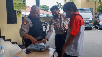 Polisi memeriksa barang bawaan pengunjung di area Polres Jakarta Selatan, Rabu (7/12/2022). [Suara.com/Alfian Winanto]
