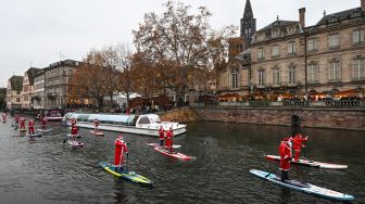 Para pendayung berpakaian Sinterklas menghadiri parade SUP (Stand Up Paddleboarding) di sungai Ill di Strasbourg, Prancis, Sabtu (3/12/2022). [SEBASTIEN BOZON/AFP]