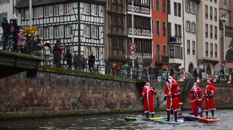 Para pendayung berpakaian Sinterklas menghadiri parade SUP (Stand Up Paddleboarding) di sungai Ill di Strasbourg, Prancis, Sabtu (3/12/2022). [SEBASTIEN BOZON/AFP]