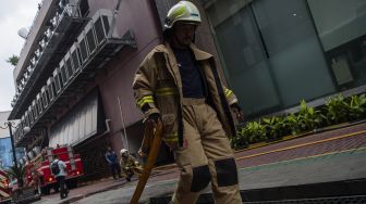 Petugas pemadam kebakaran menarik selang air usai memadamkan kebakaran di Kantor Kemenkumham, Jalan Rasuna Said, Jakarta Selatan, Kamis (8/12/2022). [ANTARA FOTO/Sigid Kurniawan]