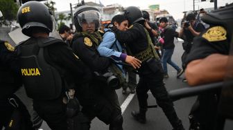 Seorang pendukung mantan Presiden Peru Pedro Castillo dibawa pergi oleh polisi di pinggiran Prefektur Lima tempat Castillo ditahan, di Lima, Peru, Rabu (7/12/2022). [ERNESTO BENAVIDES / AFP]