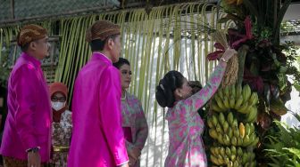 Presiden Joko Widodo, Kahiyang Ayu, dan Bobby Nasution menyaksikan Ibu Negara Iriana Joko Widodo (kanan) melepas penutup pisang tuwuhan usai prosesi "bleketepe" di atas gerbang kediamannya, di Jalan Kutai Utara, Sumber, Banjarsari, Solo, Jawa Tengah, Jumat (9/12/2022). [ANTARA FOTO/Mohammad Ayudha].