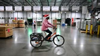 Karyawan Kantor Pos keliling dengan bersepeda di Pusat Pemrosesan dan Distribusi Los Angeles, Amerika Serikat, Rabu (30/11/2022). [Frederic J. BROWN / AFP]