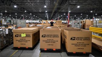 Karyawan Kantor Pos mengenakan topi Sinterklas saat menyortir surat di Pusat Pemrosesan dan Distribusi Los Angeles, Amerika Serikat, Rabu (30/11/2022). [Frederic J. BROWN / AFP]