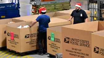 Karyawan Kantor Pos mengenakan topi Sinterklas saat menyortir surat di Pusat Pemrosesan dan Distribusi Los Angeles, Amerika Serikat, Rabu (30/11/2022). [Frederic J. BROWN / AFP]