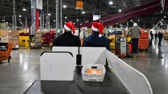 Karyawan Kantor Pos mengenakan topi Sinterklas saat menyortir surat di Pusat Pemrosesan dan Distribusi Los Angeles, Amerika Serikat, Rabu (30/11/2022). [Frederic J. BROWN / AFP]