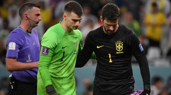 Kiper Kroasia Dominik Livakovic (kiri) dan kiper Brazil Alisson (kanan) bersiap untuk babak adu penalti saat pertandingan sepak bola perempat final Piala Dunia 2022 antara Kroasia dan Brazil di Stadion Education City di Al-Rayyan, barat Doha, Qatar, Jumat (9/12/2022). [NELSON ALMEIDA/AFP]
