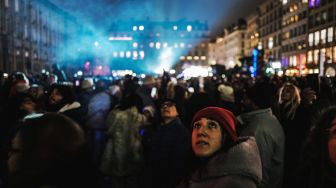 Orang-orang menonton pertunjukan cahaya dalam acara tahunan Festival Cahaya (Fete des Lumieres) di Lyon, Prancis, Kamis (8/12/2022). [OLIVIER CHASSIGNOLE / AFP]