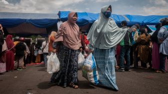 Dua warga membawa paket kebutuhan pokok saat pasar murah di Plaza Lebak, Lebak, Banten, Sabtu (10/12/2022). [ANTARA FOTO/Muhammad Bagus Khoirunas/YU]
