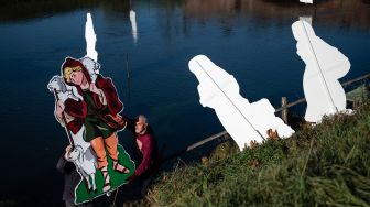 Warga saat akan memasang Instalasi Natal yang berkisah tentang kelahiran Yesus di sungai Po, Villafranca Piemonte, Turin, Italia, Selasa (6/12/2022). [MARCO BERTORELLO / AFP]
