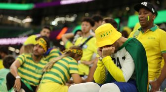 Pendukung Brazil terlihat sedih setelah timnya kalah dalam pertandingan sepak bola perempat final Piala Dunia 2022 antara Kroasia dan Brazil di Stadion Education City di Al-Rayyan, barat Doha, Qatar, Jumat (9/12/2022). [ADRIAN DENNIS / AFP]
