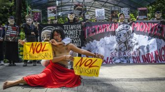 Pengunjuk rasa yang tergabung dalam Koalisi Primates Fight Back menggelar aksi teatrikal di depan Kantor Kementerian LHK, Jakarta, Senin (12/12/2022). Mereka mendesak pemerintah segera menetapkan monyet sebagai satwa dilindungi. [ANTARA FOTO/Galih Pradipta].