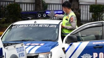 Polisi lalu lintas membersihkan kamera sistem tilang elektronik (ETLE) Mobile yang terpasang pada salah satu kendaraan patroli di Mapolda Metro Jaya, Jakarta, Selasa (13/12/2022). [ANTARA FOTO/Aditya Pradana Putra].