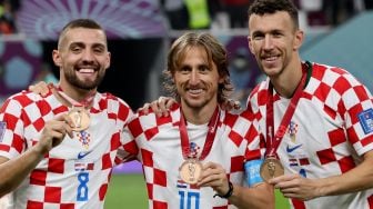 (Kiri-Kanan) Gelandang Kroasia Mateo Kovacic, Luka Modric dan Ivan Perisic memamerkan medali mereka setelah memenangkan pertandingan play-off perebutan tempat ketiga Piala Dunia 2022 antara Kroasia dan Maroko di Stadion Internasional Khalifa di Doha, Qatar, Sabtu (17/12/2022). [JACK GUEZ/AFP]