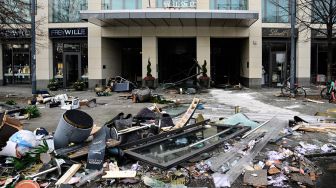 Puing-puing berserakan di depan hotel Radisson Blu, tempat akuarium besar yang terletak di lobi hotel meledak di Berlin, Jerman, Jumat (16/12/2022). [John MACDOUGALL / AFP]