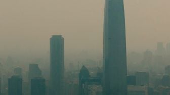 Pemandangan kota yang diselimuti asap dari kebakaran hutan yang melanda daerah sekitarnya di Santiago, Chili, Jumat (16/12/2022). [JAVIER TORRES / AFP]