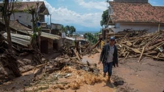 Seorang warga berjalan di lokasi terdampak banjir bandang di Sawahdadap, Cimanggung, Kabupaten Sumedang, Jawa Barat, Minggu (18/12/2022). [ANTARA FOTO/Ahmad Fauzan].