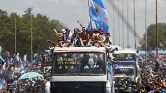 Para pemain Timnas Argentina melakukan selebrasi di atas bus dengan tanda bertuliskan "Juara Dunia" bersama pendukung setelah menjuarai turnamen Piala Dunia 2022 Qatar saat mereka melakukan tur keliling di pusat kota Buenos Aires, Argentina, Selasa (20/12/2022). [TOMAS CUESTA / AFP]
