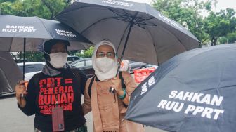 Sejumlah Ibu Pekerja Rumah Tangga (PRT) melakukan aksi Rabuan PRT: Payung Duka Seribu Ibu-Ibu PRT Indonesia di Taman Aspirasi Monas, Jakarta Pusat, Rabu (21/12/2022). [Suara.com/Alfian Winanto]