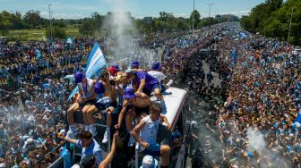 Para pemain Timnas Argentina melakukan selebrasi di atas bus dengan tanda bertuliskan "Juara Dunia" bersama pendukung setelah menjuarai turnamen Piala Dunia 2022 Qatar saat mereka melakukan tur keliling di pusat kota Buenos Aires, Argentina, Selasa (20/12/2022). [TOMAS CUESTA / AFP]