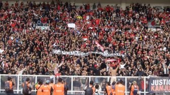 Suporter Indonesia membentangkan spanduk terkait Tragedi Kanjuruhan saat pertandingan sepak bola Grup A Piala AFF 2022 antara Indonesia dan Kamboja di Stadion Utama Gelora Bung Karno (SUGBK), Jakarta Pusat, Jumat (23/12/2022). [Suara.com/Alfian Winanto]