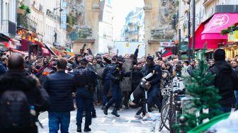 Para pengunjuk rasa bentrok dengan petugas polisi anti huru hara Prancis menyusul insiden penembakan kepada komunitas Suku Kurdi di Paris, Prancis, Jumat (23/12/2022). [Thomas SAMSON / AFP]