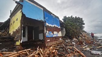 Warga melintas di dekat bangunan rumah yang roboh di Lingkungan Mapak Indah, Kelurahan Jempong Baru, Mataram, NTB, Sabtu (24/12/2022). [ANTARA FOTO/Ahmad Subaidi/YU]
