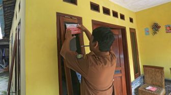 Petugas menempelkan stiker Keluarga Miskin di salah satu rumah Keluarga Penerima Manfaat (KPM) bantuan sosial di Indramayu, Jawa Barat, Senin (26/12/2022). [ANTARA FOTO/Dedhez Anggara].