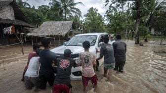 Warga mendorong mobil yang mogok saat banjir menggenangi kawasan Patia, Pandeglang, Banten, Selasa (27/12/2022). [ANTARA FOTO/Muhammad Bagus Khoirunas].