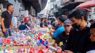 Pedagang Terompet melayani pembeli di Pasar Asemka, Jakarta Barat, Jumat (30/12/2022). [Suara.com/Alfian Winanto]