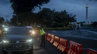 Polisi Lalu Lintas menyampaikan informasi kepada pengguna kendaraan bermotor terkait penutupan jalan di Jalan Medan Merdeka Utara, Jakarta, Sabtu (31/12/2022). [ANTARA FOTO/Aprillio Akbar].