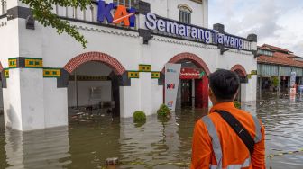 Petugas stasiun berdiri di halaman Stasiun Tawang yang terendam banjir di Semarang, Jawa Tengah, Sabtu (31/12/2022). [ANTARA FOTO/Aji Styawan].