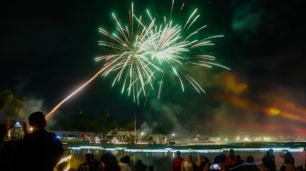Warga menyaksikan pesta kembang api saat perayaan malam Tahun Baru 2023 di Danau Archipelago, Taman Mini Indonesia Indah (TMII), Jakarta Timur, Minggu (1/1/2023). [Suara.com/Alfian Winanto]