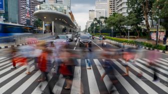 Pekerja melintas saat jam pulang kerja di Kawasan Sudirman - Thamrin, Jakarta Pusat, Senin (2/1/2023). [Suara.com/Alfian Winanto] 