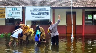 Anggota polisi beserta guru dan penjaga sekolah berswafoto usai mengecek kondisi sekolah yang terdampak banjir di SDN 3 Jati, Kudus, Jawa Tengah, Senin (2/1/2023).  [ANTARA FOTO/Yusuf Nugroho/].