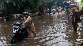 Warga mendorong kendaraannya melewati banjir di Jalan Kemang Utara IX, Jakarta Selatan, Rabu (4/1/2023). [Suara.com/Alfian Wina Winanto]