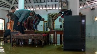 Sejumlah warga melaksankan Salat Asar berjamaah di atas meja yang diletakkan di lantai Masjid Jami Al Muttaqin yang terendam banjir di Desa Prampelan, Kecamatan Sayung, Kabupaten Demak, Jawa Tengah, Selasa, (3/1/2023). [ANTARA FOTO/Aji Styawan].