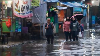 Warga berjalan melewati banjir di Jalan Kemang Utara IX, Jakarta Selatan, Rabu (4/1/2023). [Suara.com/Alfian Wina Winanto]