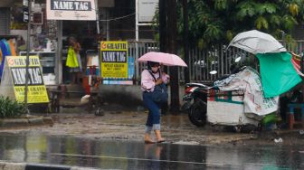 Warga berjalan menggunakan payung saat hujan lebat di kawasan Cililitan, Jakarta Timur, Rabu (4/1/2023). [Suara.com/Alfian Winanto]