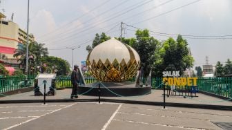 Warga mengamati Tugu Salak Condet di Jalan Raya Condet, Jakarta Timur, Senin (13/1/2023). [Suara.com/Alfian Winanto]