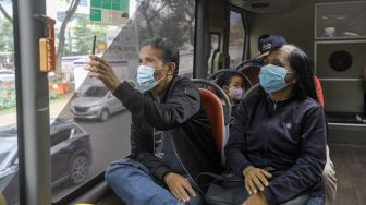 Warga saat menaiki bus tingkat Transjakarta dengan atap terbuka di Jakarta, Sabtu (14/1/2023). [Suara.com/Alfian Winanto]