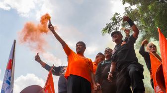 Presiden Partai Buruh Said Iqbal menyalakan flare saat memimpin massa aksi di Kawasan Patung Kuda Arjuna, Jakarta Pusat, Sabtu (14/1/2023). [Suara.com/Alfian Winanto]