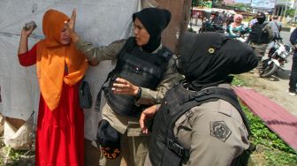 Seorang pedagang menghadang personel Satpol PP yang akan melakukan penertiban dan pembongkaran bangunan pedagang di Jalan Stadion Tunas Bangsa, Desa Mon Geudong, Lhokseumawe, Aceh, Senin (16/1/2023). [ANTARA FOTO/Rahmad].