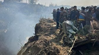 Tim penyelamat dan warga berkumpul di lokasi kecelakaan pesawat Yeti Airlines di Pokhara, Nepal, Minggu (15/1/2023). [Krishna Mani BARAL / AFP]
