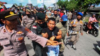 Petugas Satpol PP berusaha mengamankan salah satu pedagang saat akan dilakukan penertiban dan pembongkaran bangunan pedagang di Jalan Stadion Tunas Bangsa, Desa Mon Geudong, Lhokseumawe, Aceh, Senin (16/1/2023). [ANTARA FOTO/Rahmad]