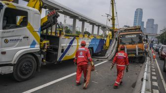 Petugas melakukan evakuasi truk bermuatan batu bara yang mengalami kecelakaan beruntun di Jalan Tol Dalam Kota, Cawang-Grogol KM 5400, di Jakarta, Rabu (18/1/2023). [ANTARA FOTO/Galih Pradipta].