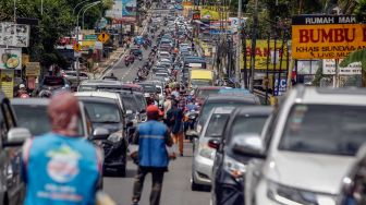 Sejumlah kendaraan wisatawan melintas di Jalan Raya Puncak, Megamendung, Kabupaten Bogor, Jawa Barat, Minggu (22/1/2023). [ANTARA FOTO/Yulius Satria Wijaya/aww]