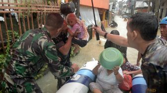Anggota TNI menggendong seorang anak yang dievakuasi dari rumahnya yang terendam banjir di Manado, Sulawesi Utara, Jumat (27/1/2023). [ANTARA FOTO/Adwit B Pramono].