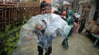 Anggota TNI menggendong seorang manula dari rumahnya yang terendam banjir di Manado, Sulawesi Utara, Jumat (27/1/2023). [ANTARA FOTO/Adwit B Pramono]